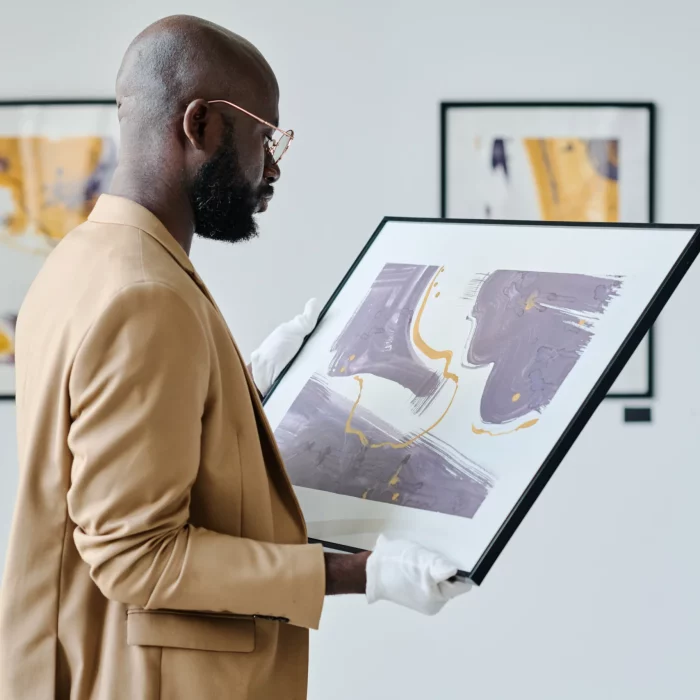 Médiateur culturel Un médiateur culturel tient un tableau dans les mains pour une exposition d'art moderne